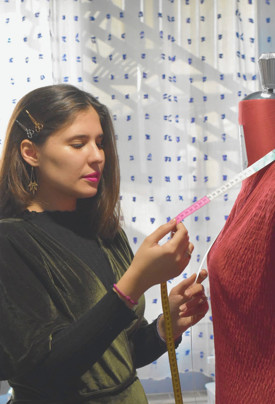 Maria Chrysafi taking measurements on a dress form in her studio